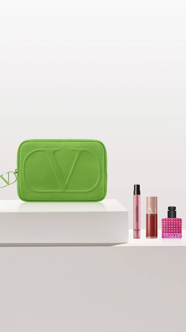 Neceser verde con logotipo de CV y frascos de perfumes en una superficie clara.