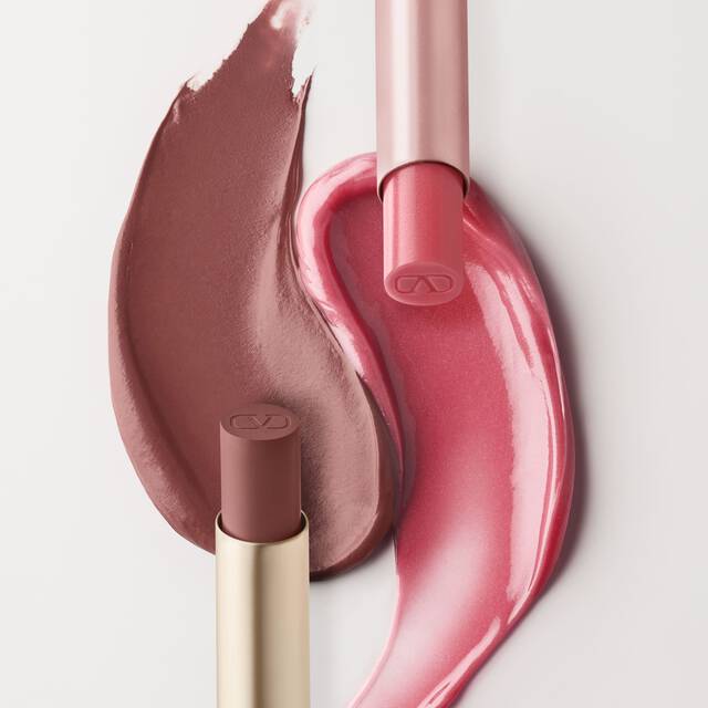 Una imagen dividida que muestra productos cosmeticos. A la izquierda, se ven dos muestras de productos labiales rosados, una en un tono rosa-marron mas claro y la otra en un rosa mas brillante y brillante. Un tubo de balsamo labial Valentino Spike y un tubo de brillo labial estan colocados junto a ellos. El lado derecho muestra una caja de Spike Valentino Disco Balm y una caja de Spike Valentino Matte, con sus respectivas muestras de color dispuestas debajo.
